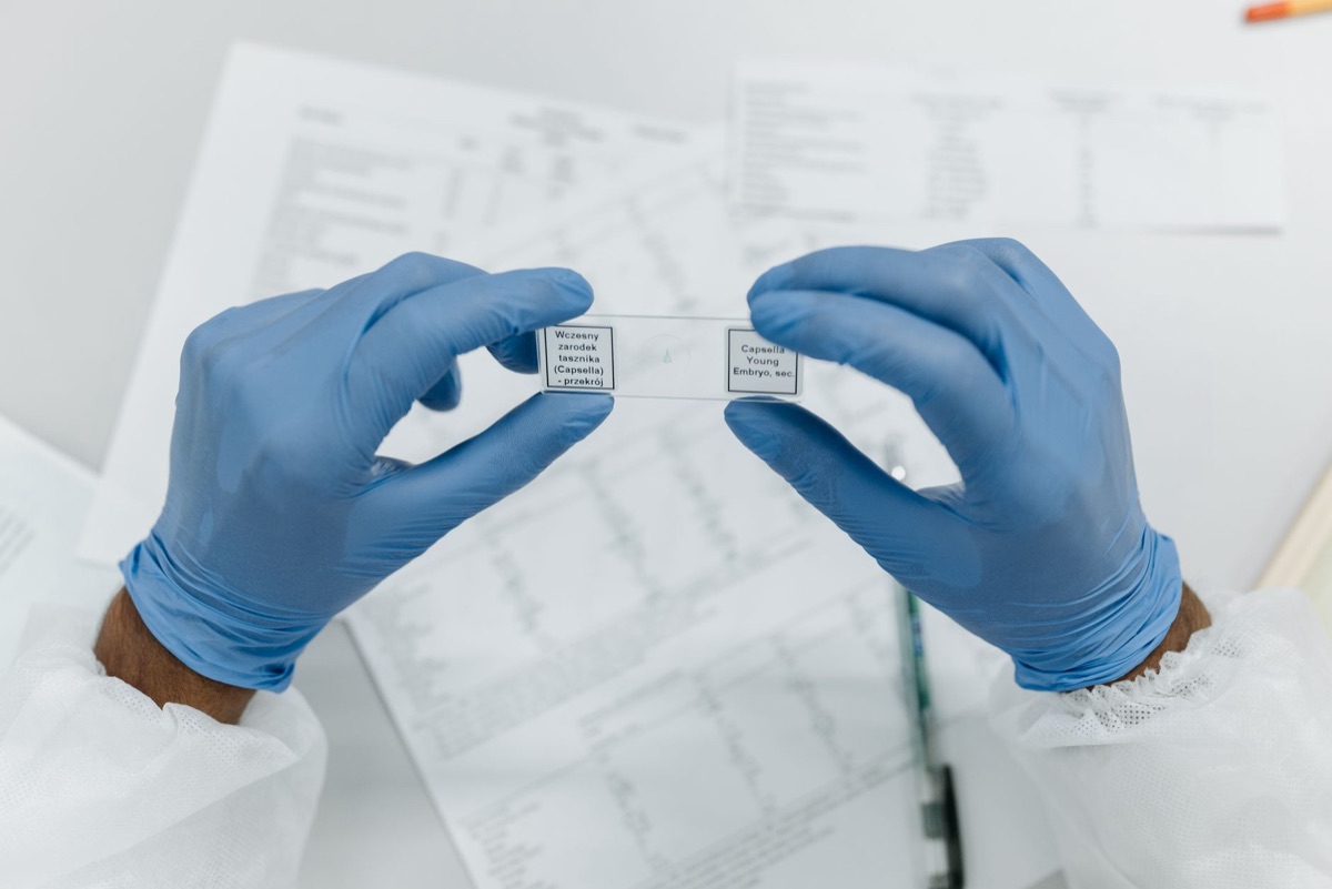 A scientist examining a slide under a microscope in a bright laboratory.
